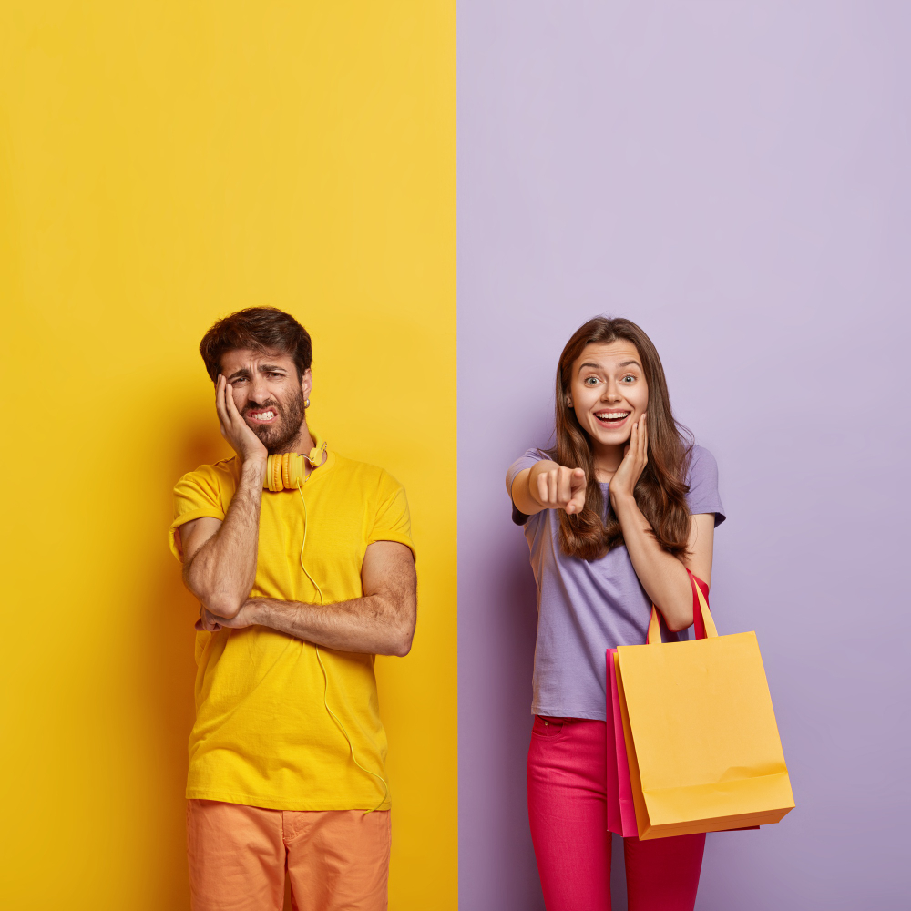 A imagem contém um homem ao lado esquerdo, fundo amarelo, camiseta amarela, calça laranja, fone de ouvido amarelo, expressão de tristeza. Na direita tem uma mulher, fundo cinza, calça laranja, blusa cinza e sacola amarela, com expressão de felicidade e apontando para a frente.
