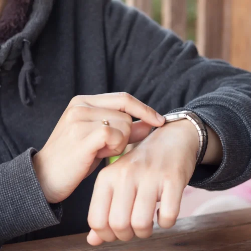 Woman checks the time on a wrist watch, stock photo